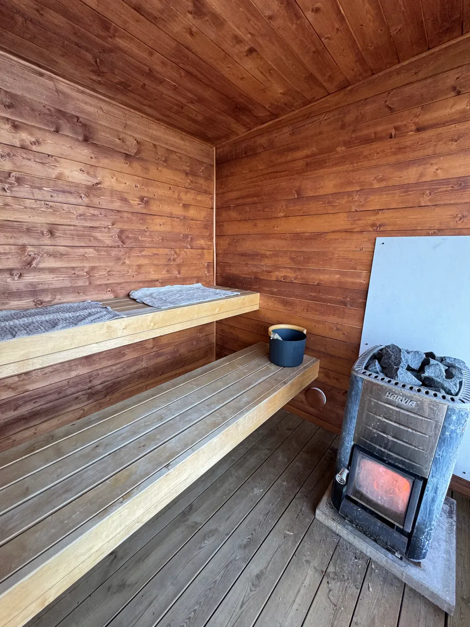 Bastuns träklädda interiör med lavar och vedeldad kamin.