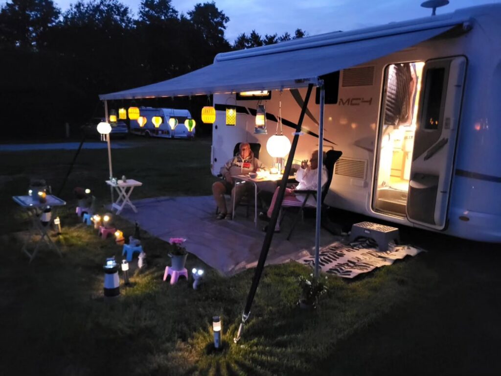 Campinggäster med ljuslyktor i sommarkvällen.